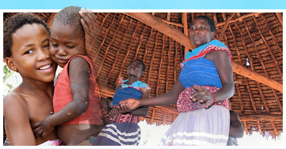 a kid holding a baby and women dancing in the hut